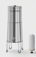 Stainless steel gravity water filter system on a wire stand with spigot, shown beside a white filter element