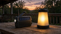 Hand-crank emergency radio and glowing solar lantern on a wooden porch table at dusk
