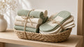 Rolled reusable cloth towels and folded cloth pads tied with twine in a woven basket on a wooden shelf